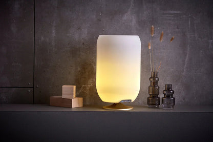 Lámpara de mesa LED moderna iluminada, con diseño minimalista, sobre mueble gris en interior elegante